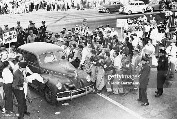 Burbank, California: "Trouble starts at film studio gates." Pickets are shown here kicking and pushing at car which tried to pass picket line at...