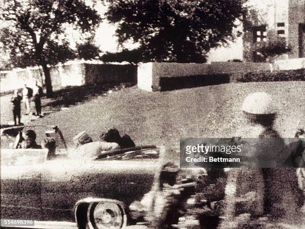 First Lady Jacqueline Kennedy leans over to assist her husband just after he is shot as the Presidential motorcade passes through Dealey Plaza on Elm...