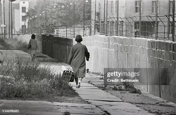 Berlin: Two West Berlin women go about their daily chores in spite of this Red version of the Great Wall of China here August 27th. In further effort...