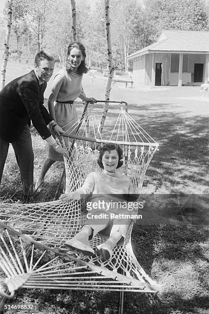 Pamela Churchill Hayward rocked in hammock by her son Winston and his finacee Minnie D'Erlanger. | Location: Mount Kisko, New York, USA.