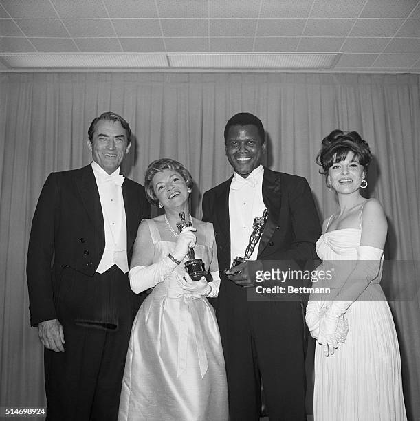 Backstage at the 1964 Academy Awards are Gregory Peck, who presented Oscar for Best Performance by an Actress, Anabella, who accepted the Oscar for...