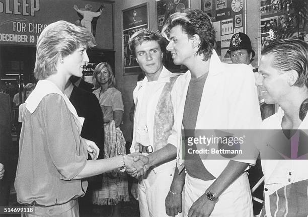 London: Princess Diana of Wales shakes hands with John Taylor of the Duran Duran pop group 7/20, as lead singer Simon Le Bon and fellow group member...