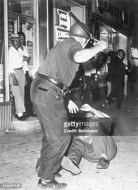 Police officer beats a protester with a nightstick during riots in Harlem sparked by the killing of a 15 year old boy by police.