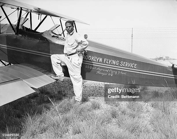 Flying ace Colonel Hubert Julian stands next to a biplane at Roosevelt Field, Long Island.