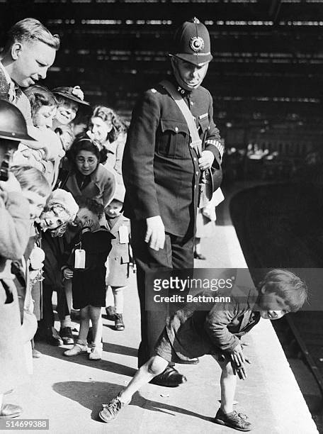 Cornelius Aedo peers down a London train platform with other children and their mothers. They are waiting for trains to take them to safer towns...
