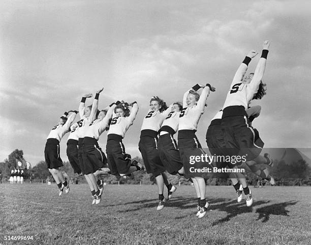 Springfield High School cheerleaders jump and cheer while performing on a sports field. Delaware County, Pennsylvania, March 5, 1941.