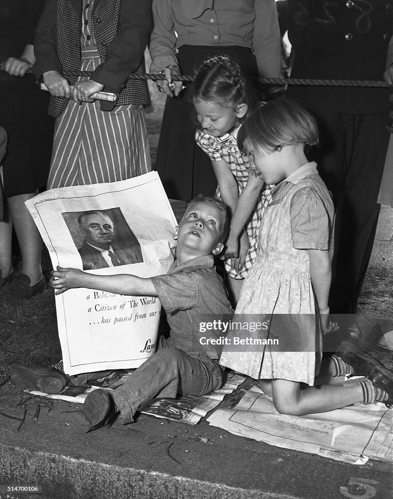 Children Gather Around a Newspaper