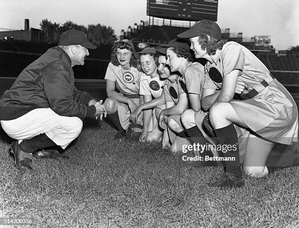 Former hockey player Eddie Stumpf manages the Rockford Peaches of the All-American Girl's Professional Baseball League. Five of his players crouch in...