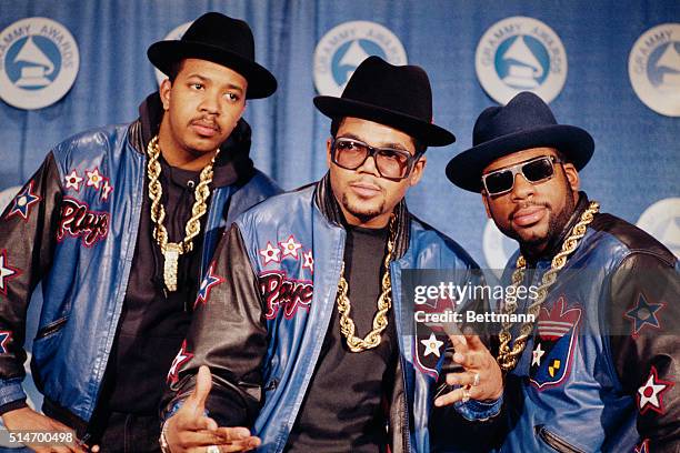 Poses in full regalia that they popularized- heavy gold chains, hats, sunglasses, and Adidas track suits. They have just received the Grammy Awrds....