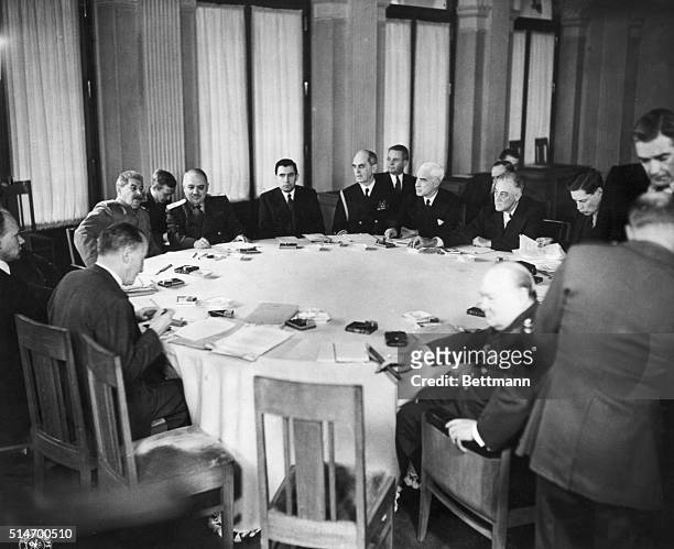 Delegates and world leaders meet around the conference table during the first meeting of the conference. To the left is Soviet Premier Joseph Stalin,...