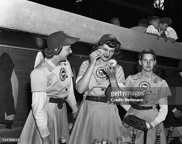 Elise Harney, pitcher for the Kenosha Comets, refreshes her makeup between innings as teammate Janice O'Hara and another player look on. The women of...
