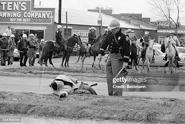 An officer accosts an unconscious woman as mounted police officers attack civil rights marchers in Selma, Alabama who were attempting to begin a 50...