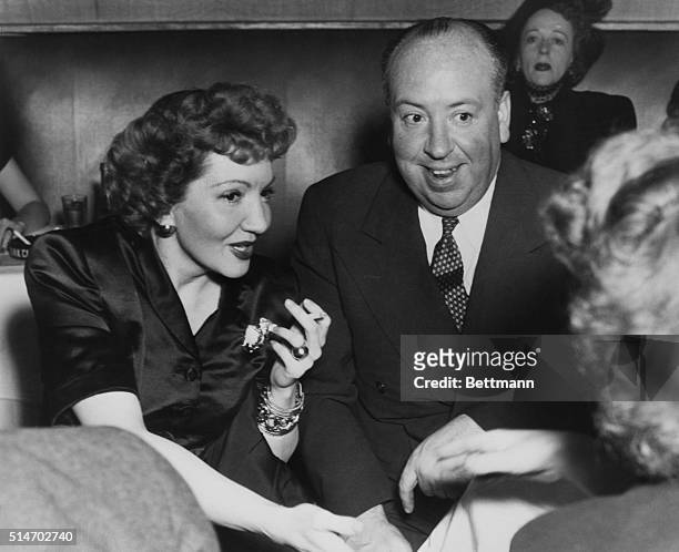 New York, NY: Famed producer Alfred Hitchcock enjoys the charming company of film actress Claudette Colbert at the Stork Club. Miss Colbert has told...