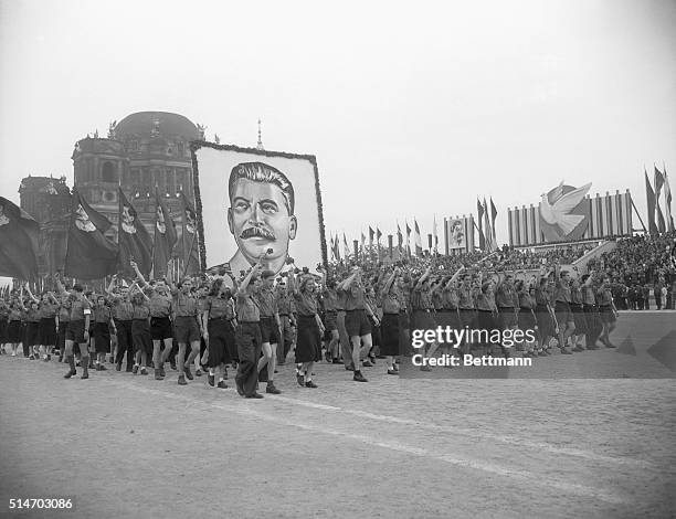 Russia: Cheering Communist youths leading the way for this huge portrait of Josef Stalin tramp past the honor tribune at right background.