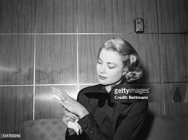 Chicago, IL: Film actress Grace Kelly, en route to Hollywood for movie work, strikes a pose to show off the engagement ring given her by Prince...