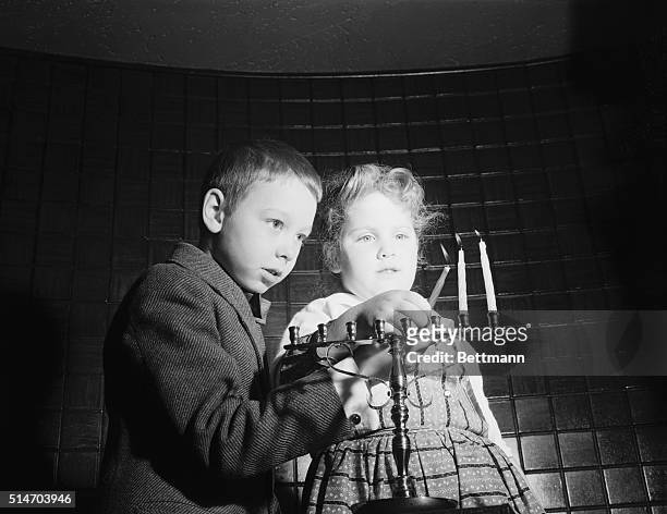 December 7, 1958-Jewish Holiday-Chanukah: New York: Festival Lights. Peter Wejksnoria and Susan Hendler light candle in the Menorah. Act is symbolic...