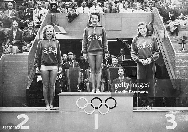 London, England: Vickie Draves of Los Angeles holds the place of honor on the winner's rostrum at empire pool after her victory in the Olympic...