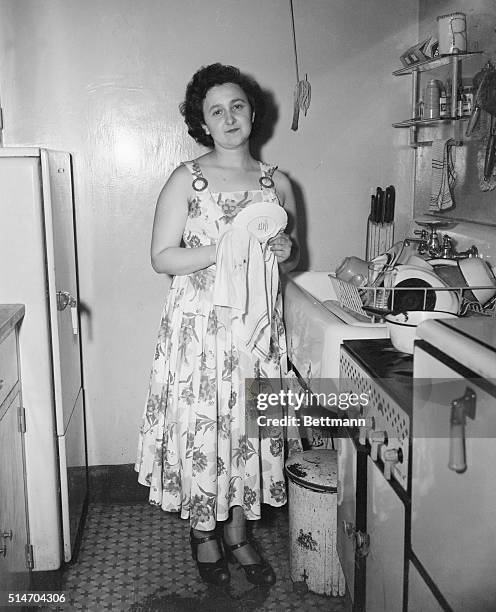 New York: Mrs. Ethel Rosenberg dries dishes in her knickerbocker village home, July 18, as she talks to reporters after her husband, Julius was...