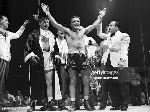 New York: Unmarked and smiling, Jake LaMotta, the middleweight champion, raises his hands in victory after winning the decision over Tiberio Mitri in...