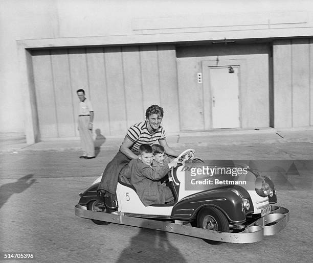 Kirk Douglas shares some automotive thrills with his two sons, Joel and Michael , in one of the miniature roadsters at Disneyland. Producer Walt...