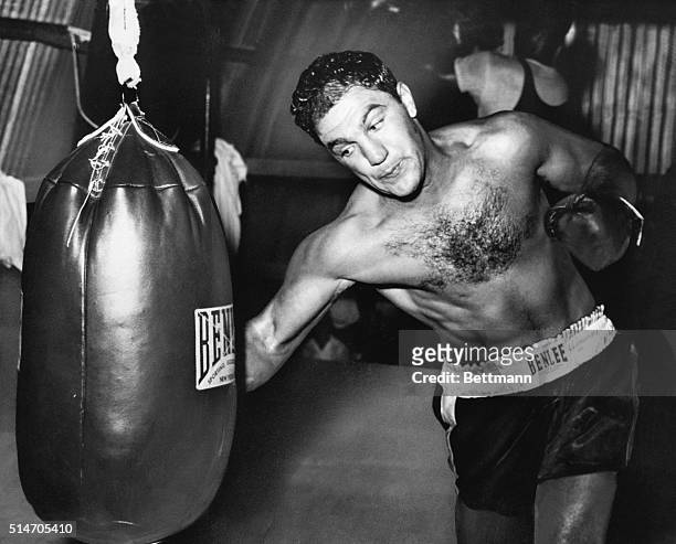 Grossinger, NY: Solid defender. World heavyweight champion Rocky Marciano gets in some licks with the big bag while training here for his forthcoming...