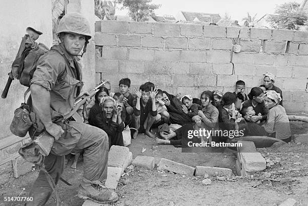 Qui Nhon, South Vietnam: Vietnamese women, children and elders huddle together, as U.S. Marine Corporal Dave Taylor of State College, Pennsylvania...