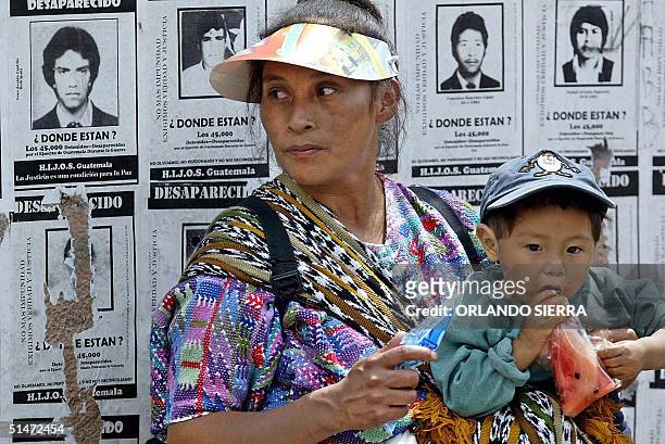 Una indigena guatemalteca y su hijo se encuentran frente a afiches relativos a los desaparecidos el 12 de octubre de 2004, durante una marcha de...