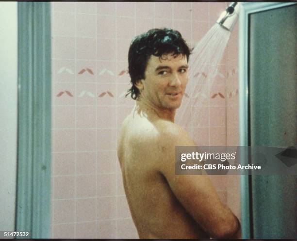 In a scene from the American television series 'Dallas,' American actor Patrick Duffy stands in the shower and looks over his shoulder in an episode...