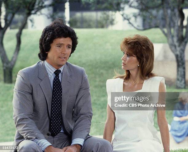 In a scene from the American television series 'Dallas,' American actors Patrick Duffy and Victoria Principal sit outside together and talk in an...