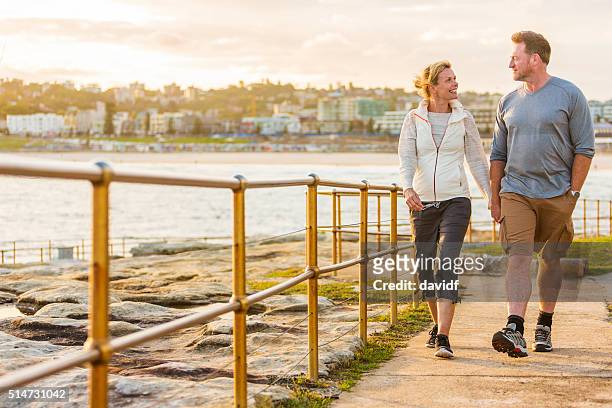 feliz ajuste ativo saudáveis de meia idade na praia casal a passear ao ar livre - middle age imagens e fotografias de stock