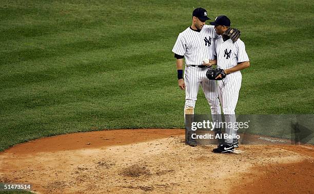 Derek Jeter of the New York Yankees puts his arm around pitcher Mariano Rivera as he enters the game in the eighth inning during game one of the...