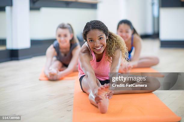 stretching to touch their toes - teens stretching in gym stock pictures, royalty-free photos & images
