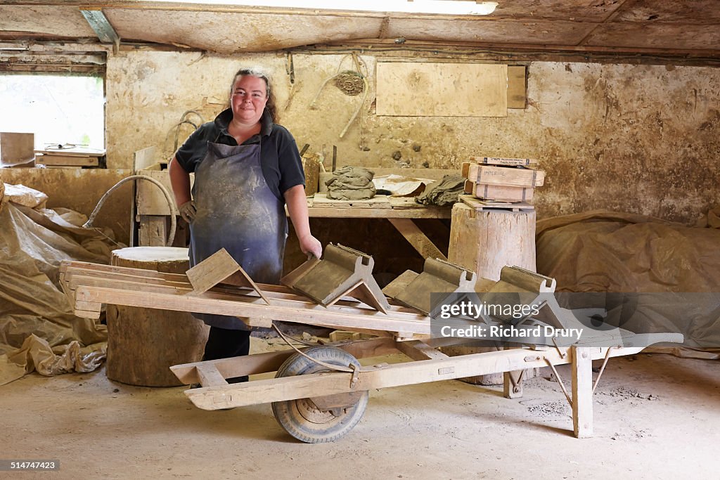 Female brickmaker standing by her bench