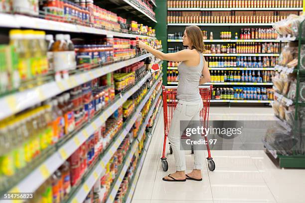 frau wählt-sauce im supermarkt - pikante sauce stock-fotos und bilder