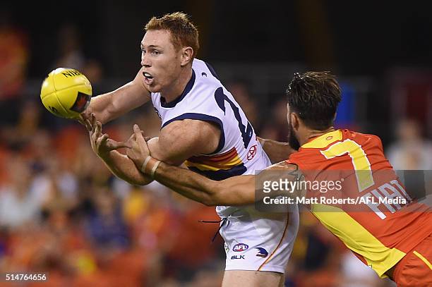 Tom Lynch of the Crows handballs in the tackle of Nick Malceski of the Suns during the NAB Challenge AFL match between the Gold Coast Suns and the...