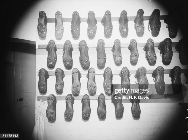 Rows of football boots hanging in the boot room at Arsenals Highbury Stadium, November 1938. Each set of boots has the players initials written on.