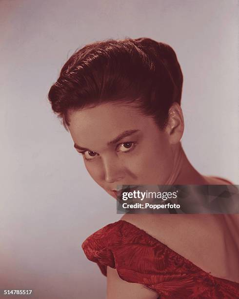 American actress and singer Kathryn Crosby posed wearing a red off the shoulder dress circa 1955.