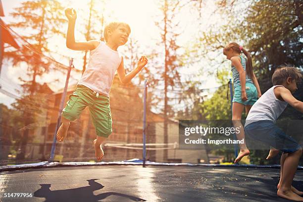 kinder springen auf trampolin-garten - trampoline stock-fotos und bilder