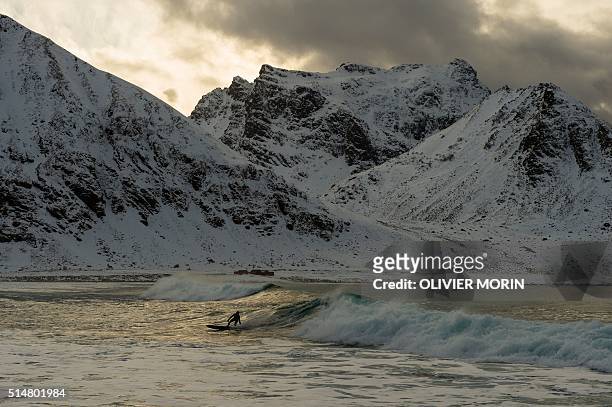 Surfer rides a wave at the snowy beach of Unstad, in Lofoten Island, Arctic Circle, on March 10, 2016. Surfers from all over the world comes to...