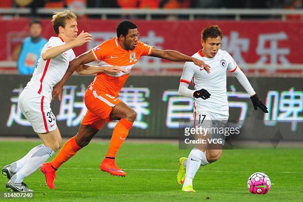 Jucilei of Shandong Luneng and Michael Thwaite of Liaoning Whowin compete for the ball during the Chinese Football Association Super League match...