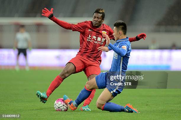 Asamoah Gyan of Shanghai SIPG competes for the ball with Li Yunqiu of Shanghai Shenhua during their Chinese Super League football match in Shanghai...