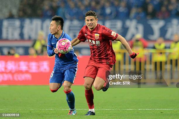 Elkeson De Oliveira Cardoso of Shanghai SIPG competes for the ball with Li Yunqiu of Shanghai Shenhua during their Chinese Super League football...