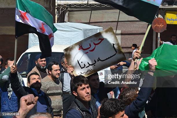 Syrians oppositions chant slogans and hold Syrian flags during a protest against Assad Regime under the slogan of ' Our Revolution continues' after...