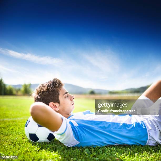 soccer player relaxing on the pitch - ball pit stockfoto's en -beelden