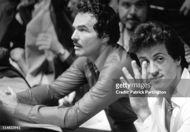 View of American actors Burt Reynolds and Sylvestor Stallone at an unspecified boxing match, Jupiter, Florida, 1979. Stallone waves to someone...