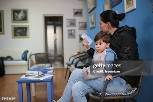 young woman and her son at the doctor - waiting room stock pictures, royalty-free photos & images