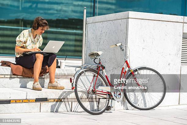 woman working on laptop sitting near oslo opera house - macbook stock pictures, royalty-free photos & images