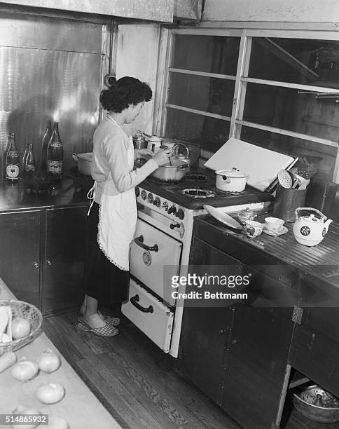 Young Japanese housewife cooks using a new gas range in the kitchen of her Tokyo home.