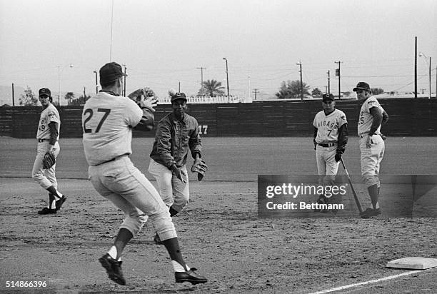 Year-old Chicago Cubs first baseman Ernie Banks tosses a ball to pitcher Phil Regan, who covers first base. Banks reported early to spring training...