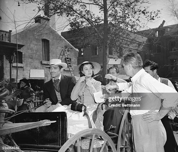 Director Victor Fleming talks to actress Vivien Leigh during the filming of Gone With the Wind . Actor Clark Gable is seated beside her.